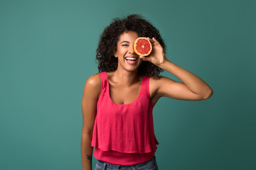 Happy african-american woman holding half of grapefruit