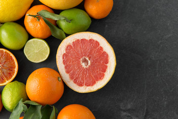 food, healthy eating and vegetarian concept - close up of citrus fruits on stone table