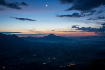 Cold morning mountain range in the fog, view on countryside landscape, blue winter with dawn dark sky.