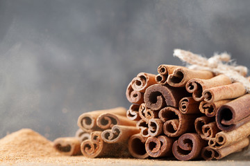 Bunch of cinnamon sticks and ground cinnamon on dust effect background. Aromatic spice.