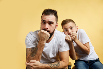 boy and father bite nails and look camera on yellow background