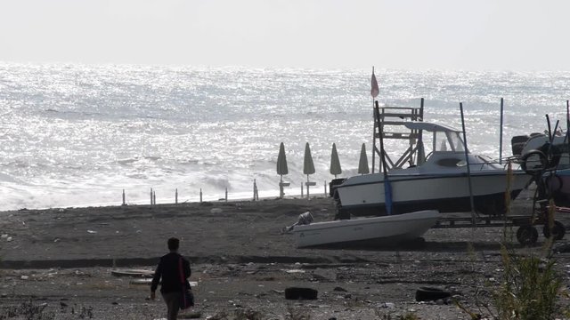passaggio attraverso la spiaggia con ricovero di natanti e sullo sfondo il mare con forte vento