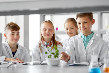 education, science and school concept - kids or students with plant at biology class