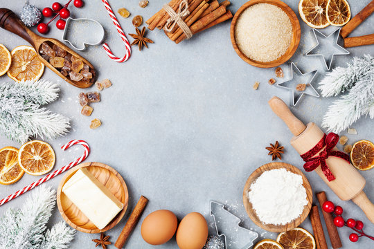 Bakery background with ingredients for cooking christmas baking decorated with fir tree. Flour, brown sugar, eggs and spices top view.