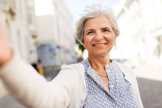 old age, retirement and people concept - happy senior woman taking selfie on city street in summer