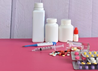 Multicolored isolated pills and capsules on the pink background