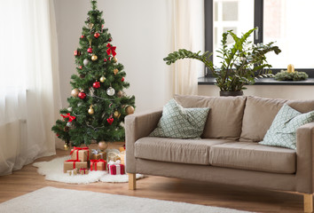 winter holidays and interior concept - christmas tree, gifts and sofa at cozy home living room