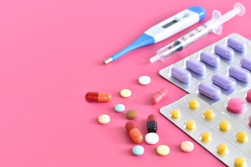 Multicolored isolated pills and capsules on the pink background