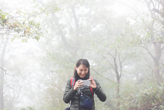ハイキング中に携帯で写真を撮り笑っている女性