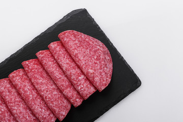 delicious sliced salami on a stone plate white background