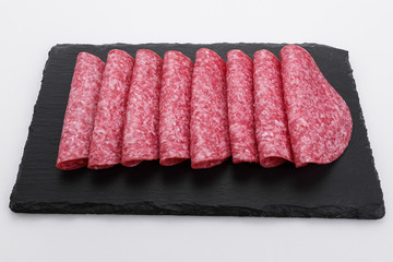 delicious sliced salami on a stone plate white background