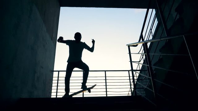 A person jumps on his board in a staircase and fails. Slow motion.