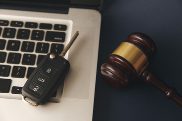 Close-up Of Gavel And Car Key On Sounding Block Against Grey Background