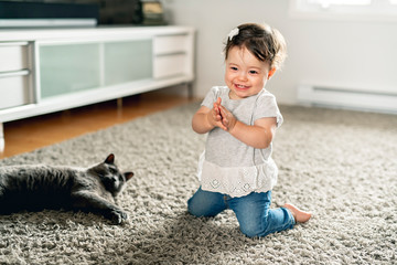 Little child girl having good time on livingroom with cat