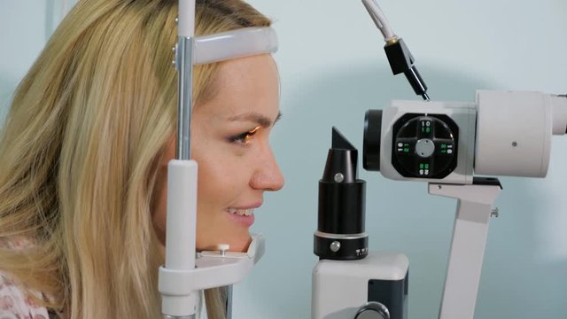 Woman having eyes measured with test device in optician shop, close up