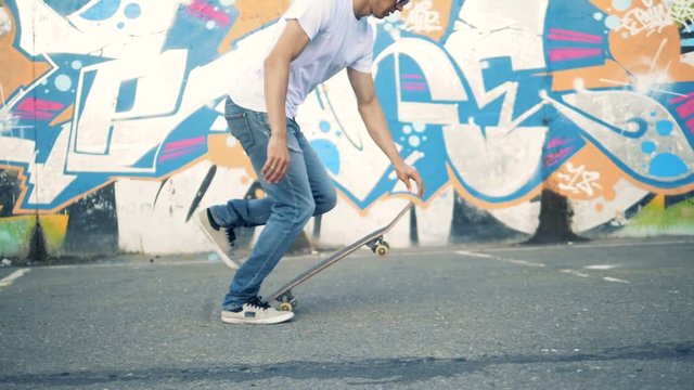 Person riding a skateboard on a wall background, slow motion.