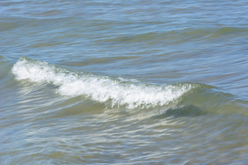 natural background. a small running wave with foam near the shore