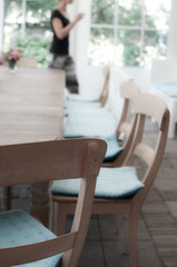 wooden table and chairs with silhouette of woman walking by