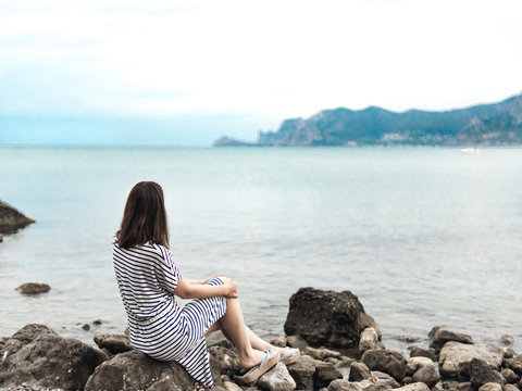 Pensive woman on rocky coastline