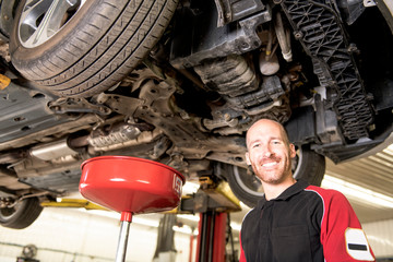 Fototapeta na wymiar handsome mechanic based on car in auto repair shop