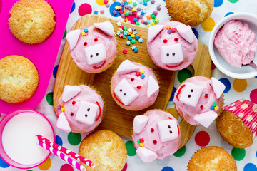 Fototapeta na wymiar Pink pig cupcakes - homemade cupcakes decorated with cream cheese frosting and marshmallow shaped funny piggies, christmas and new year 2019 sweet treat for kids