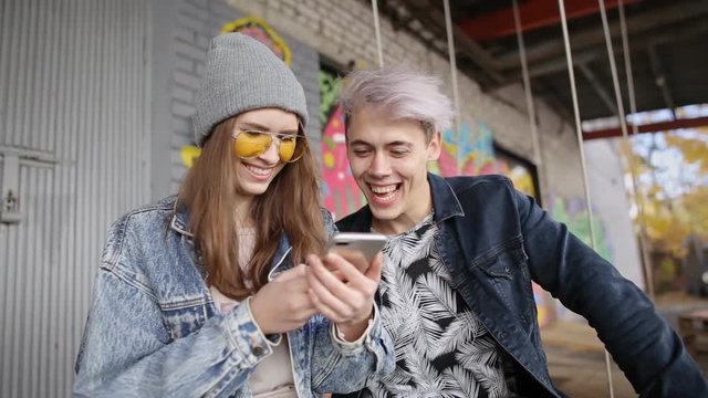 Young couple watching online media content in a smart phone in urban background