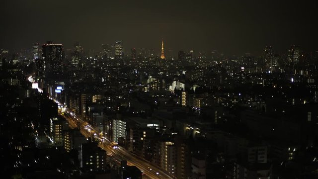 Wide shot of crowded cityscape with modern building, cars moving on street at night, Tokyo, Japan