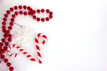 Two red and white candy canes, snowflake and red necklace. Christmas and New Year holiday background concept. Blank space for greetings.