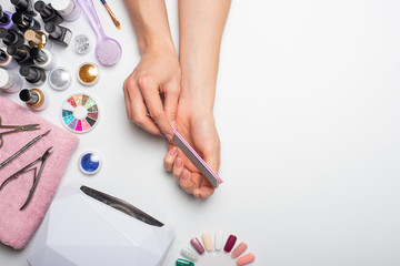 Nail care. beautiful women hands making nails painted with pink gentle nail polish on a white...