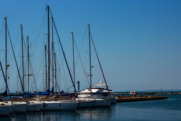 several yachts with lowered sails at the sea pier
