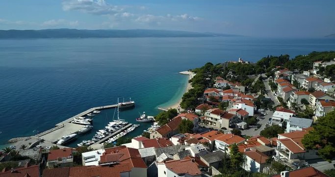 Drone shot of houses at coastline with boats moored in sea, Brela, Croatia