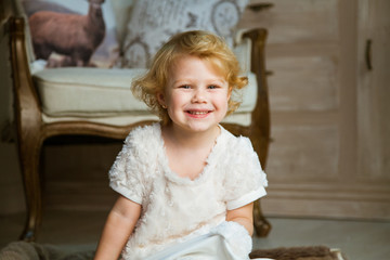 Fototapeta premium little happy girl sits in an armchair and waits for gifts for the holiday of Christmas and New Year