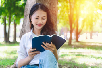 Beautiful woman reading a book on the grass of the park and enjoy learning she was happy to relax on holiday.