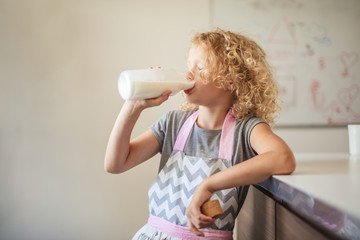 healthy food, drinks, childhood concept - smiling little girl with curly blonde hair dressed in...