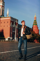 Brutal man in a black coded jacket walks around the square of a European city and looks around...