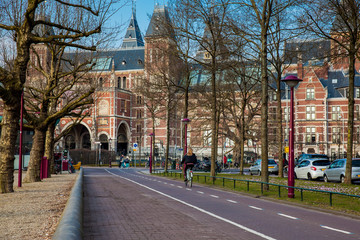 Fototapeta na wymiar Cyclists at the bikeway next to the National Museum of Amsterdam in a cold early spring day