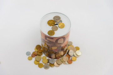 Studio photo of a decorative piggy bank with scattered cash coins on a white background