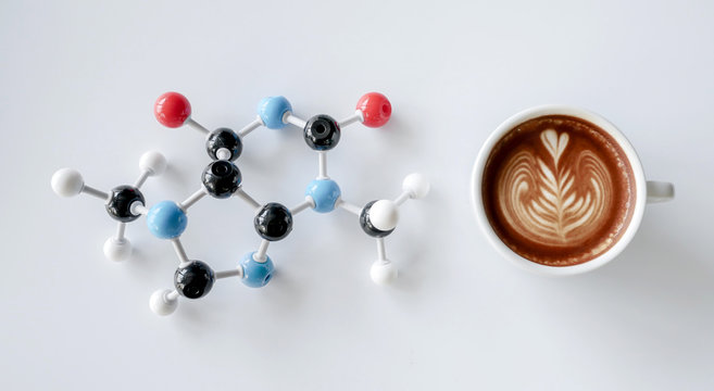 Coffee cup of cappuccino with latte art and molecule of caffeine structure on white table