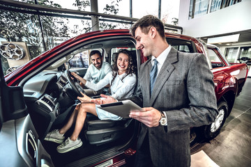 lucky family sitting in new automobile in auto salon