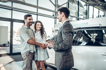 Young Couple is Meeting with Seller in Auto Salon