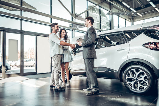 Young couple shaking hands with sales agent after a successful car buying