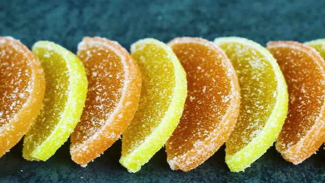 Yummy sweet citrus candy with sugar on dark texture surface. Close up.
