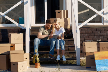 Husband and wife kissing in front of new buying home with boxes. bought first home