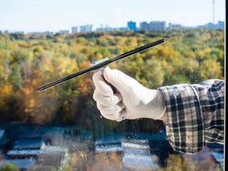 wiping a home window glass by squeegee