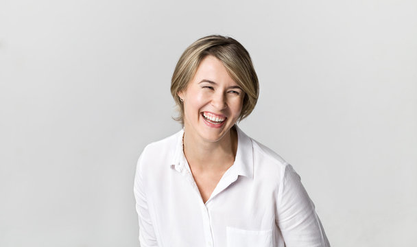 Happy young blonde woman wearing white shirt smiling portrait against white background