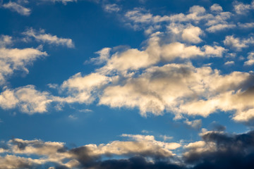 A beautiful horizontal texture of a blue sky with bright white and orange and gray clouds