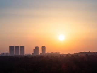 sun over city and forest in yellow sunrise