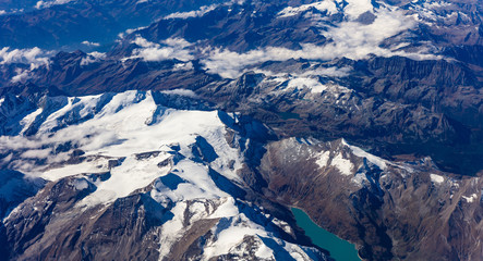 Mountains with snow from above. View out of an airplane window.