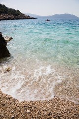 Obraz premium KAS, TURKEY Lone kayaker on water, beach in foreground.