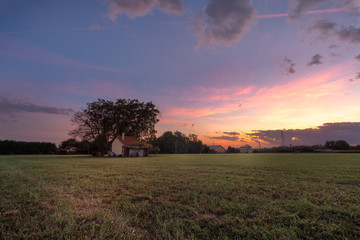 isoloated house in the field at sunset with cloudy sky